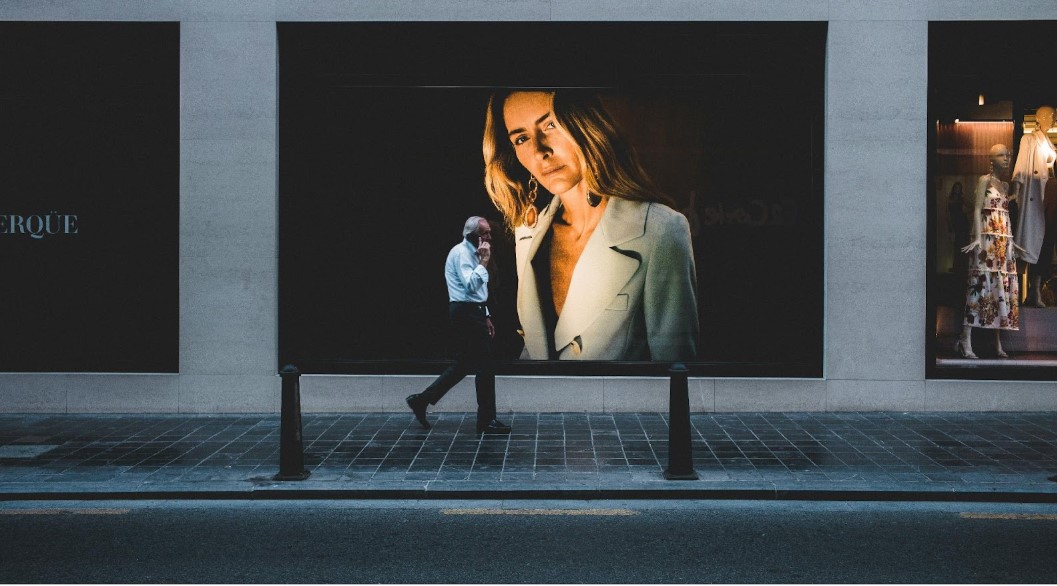 A man walking with large advertising billboards behind him.