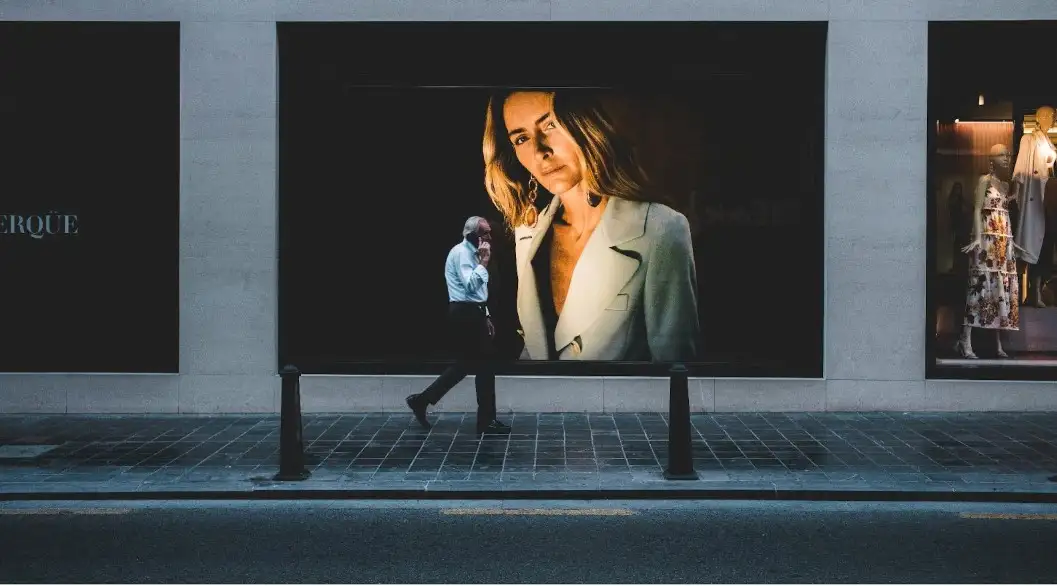 A man walking with large advertising billboards behind him.